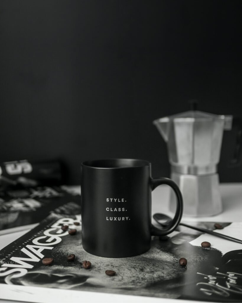 A black coffee mug sits on top of a newspaper in a corporate office refreshment scene.