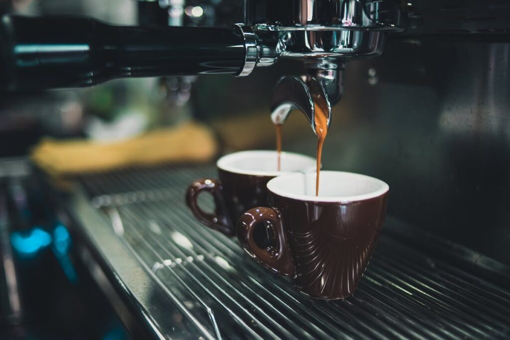 Two coffee cups being poured from an espresso machine, providing coffee break supplies.
