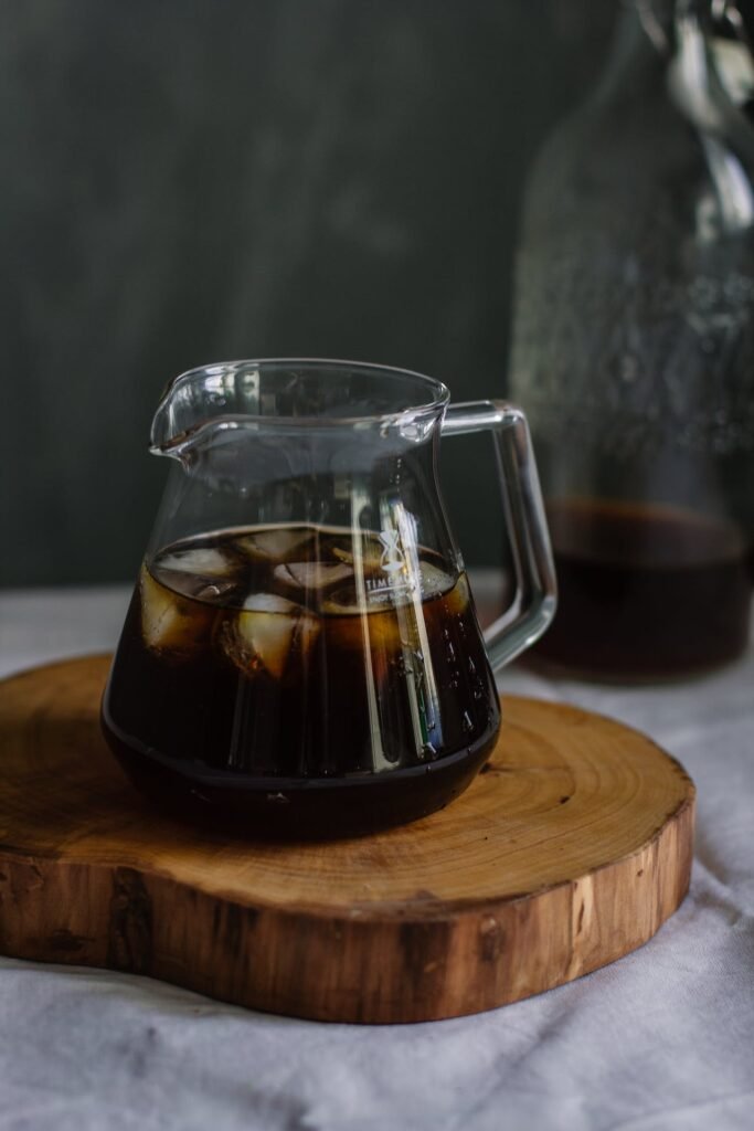 A pitcher of iced coffee on a wooden cutting board, perfect for your corporate office refreshment needs.